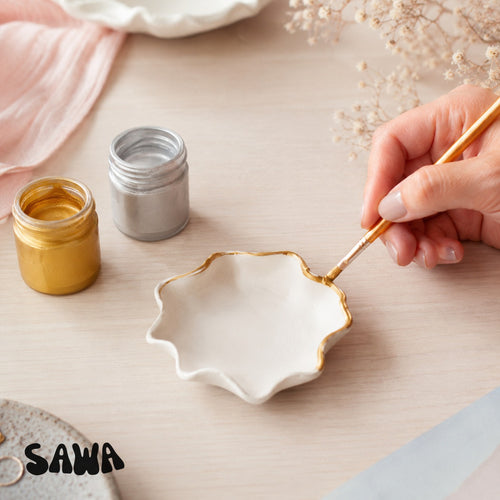 Hand painting a gold rim onto a white clay dish with Sawa gold paint