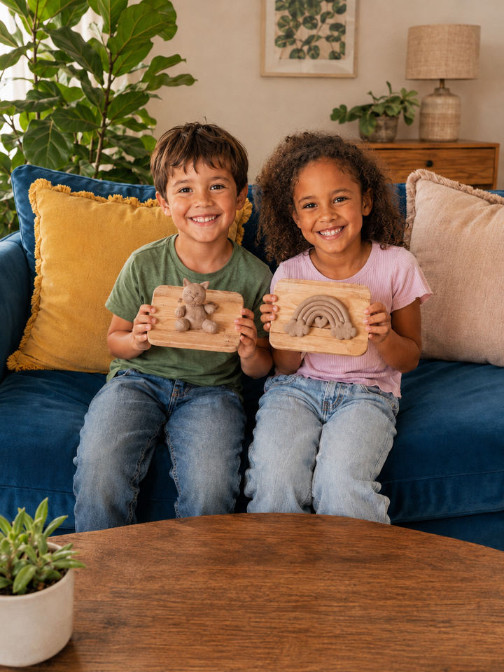 Two kids proudly showing their finished clay creations on the sofa