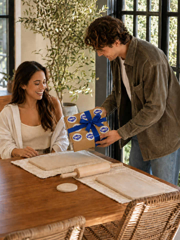 Man gifting a Sawa pottery kit wrapped with an indigo ribbon at a bright dining table